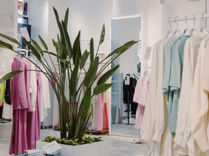 Pastel tonlu kıyafetleri ve yeşil bitkisiyle aydınlık butik