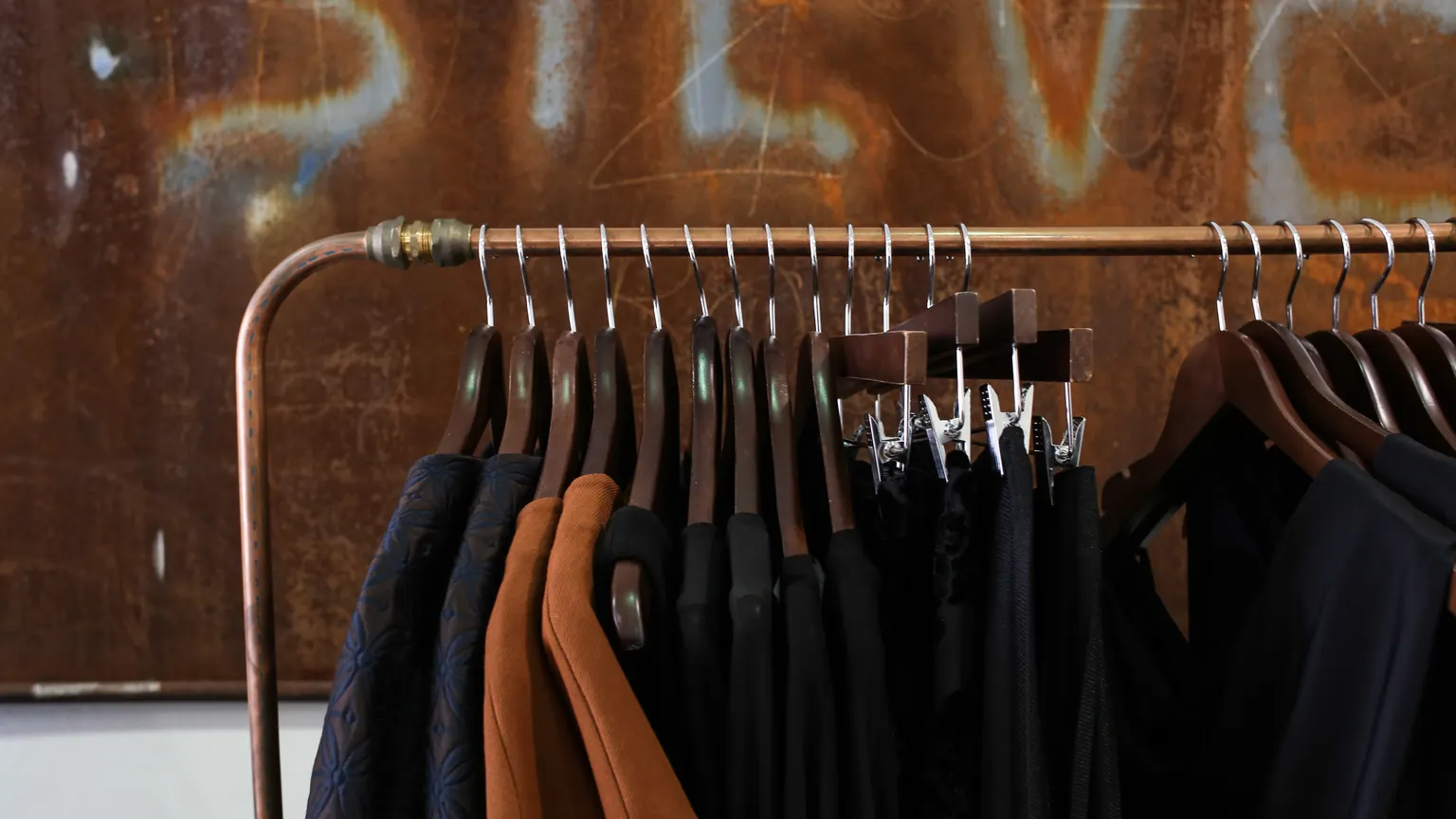 Ahşap askılarda sıralanmış kıyafetlerle bir butik içi