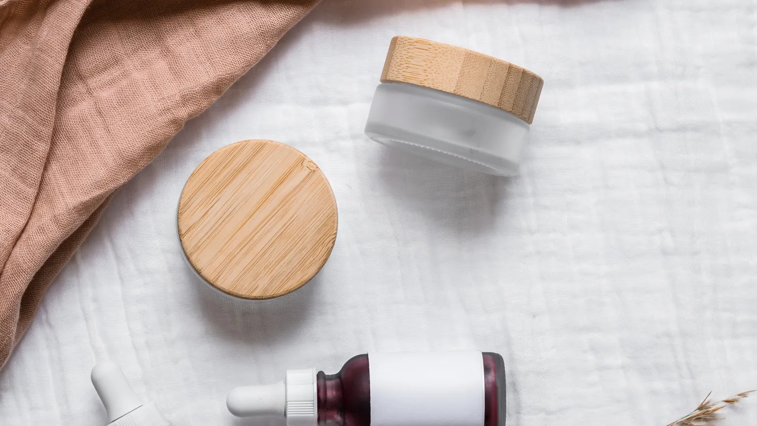 Yumuşak kumaş üzerinde serum şişeleri ve krem kavanozları